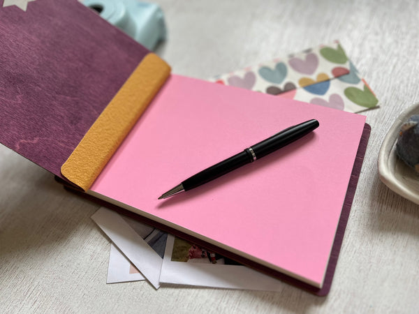 Purple book with star designs and personalized text made in wood for Bat or Bar Mitzvah- shown open to the first page which is pink and customizable in color