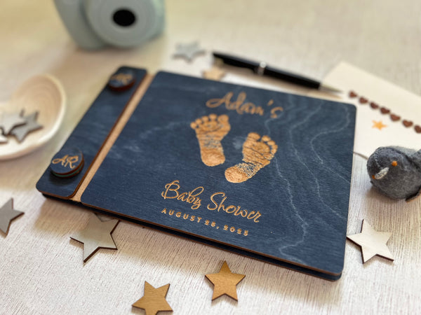 Baby shower guest book with footprints and personalized text on a wooden covers- with a navy wood stain and engraved baby foot prints with personalized text