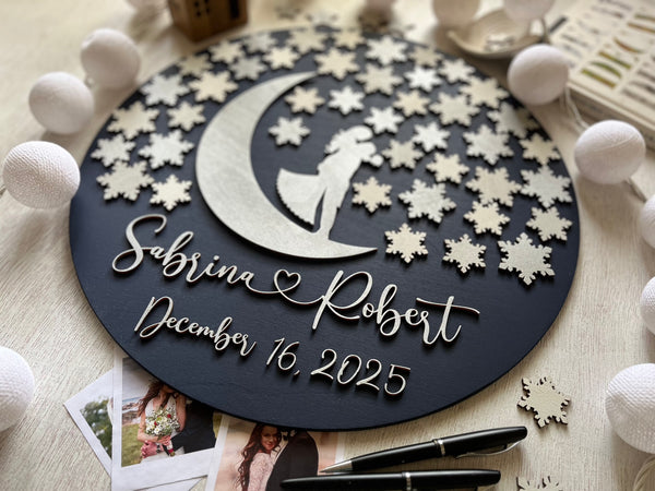 Personalized wedding plaque guest book alternative with names and date, surrounded by decorative elements on a wood surface.
