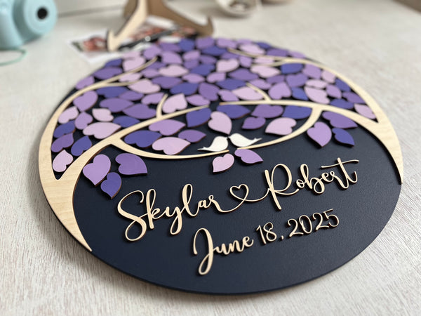 Decorative wedding guest book with purple leaf design and personalized text on a magnetic wooden surafce with removable magnetic leaves in purple, lavender, violet shades. Each guest signs a leaf and the round guest book can be hung in your home as a wedding memento. 