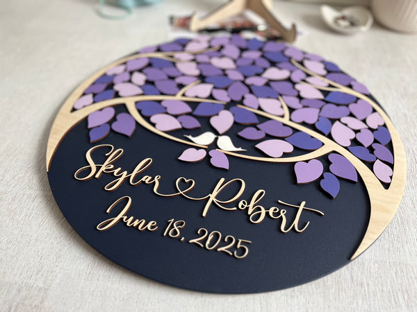 Decorative wedding guest book with purple leaf design and personalized text on a magnetic wooden surafce with removable magnetic leaves in purple, lavender, violet shades. Each guest signs a leaf and the round guest book can be hung in your home as a wedding memento. 