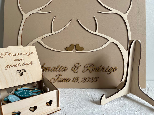 magnetic guest book for wedding made with two trees, personalized names and wedding date in gold font, magnetic leaves for guests to sign and a holder for the board plus a box for the leaves.