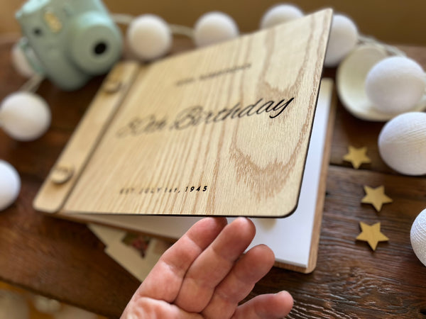 Guest book with wooden engraved covers made for an 80th Birthday celebration and custom engraved buttons for the guestbook