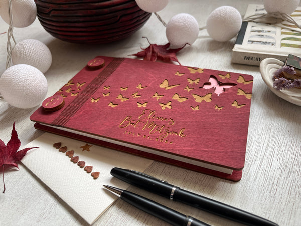 the guest book is made of wood and engraved with butterflies , the covers are stained in a burgundy stain