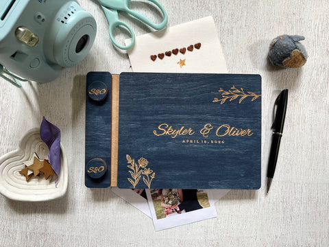 Personalized guest book with decorative floral elements with wooden engraved covers with a navy wood stain. Add your names and wedding or bachelorette party date. Customize the cover colors 