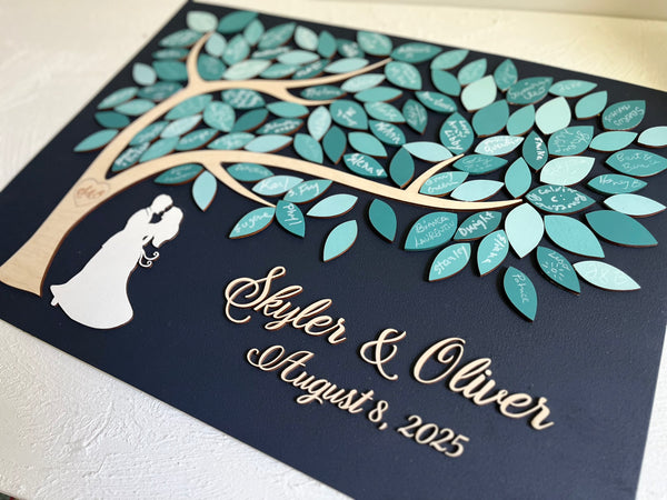 Decorative wedding guest book with tree design and personalized names on a dark navy background.