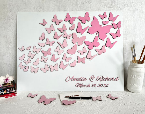Butterfly-themed guest book with pink butterflies and personalized text on a white surface.