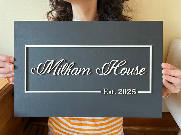 Person holding a Decorative 3D wood sign personalized with last names and 'Est. date' 