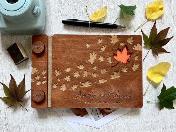 Wooden photo album with maple leaf designs and engraved names, personalized for a fall wedding. 