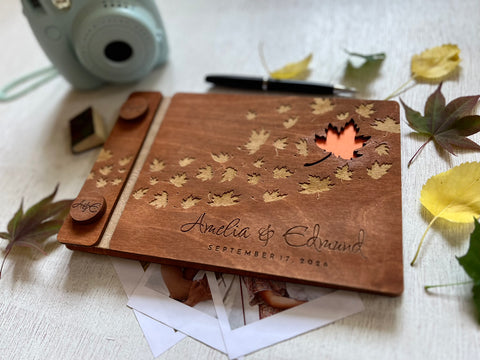 Wooden photo album with maple leaf designs and engraved names, personalized for a fall wedding. 