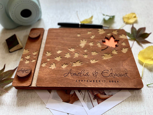 Wooden photo album with maple leaf designs and engraved names, personalized for a fall wedding. 