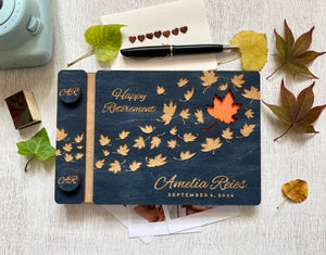 Personalized retirement guest book with autumn leaf design on a custom engraved surface with maple leaves and  personalized with the name of the retiree and the text "Happy Retirement"