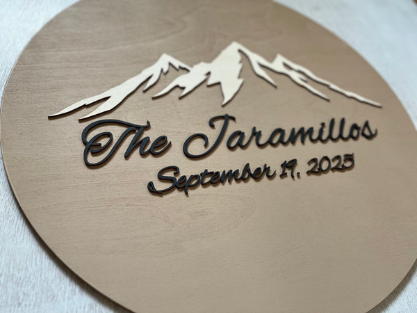 detail of Round decorative plaque with mountain design and text on a stand personalized with a last name and wedding date