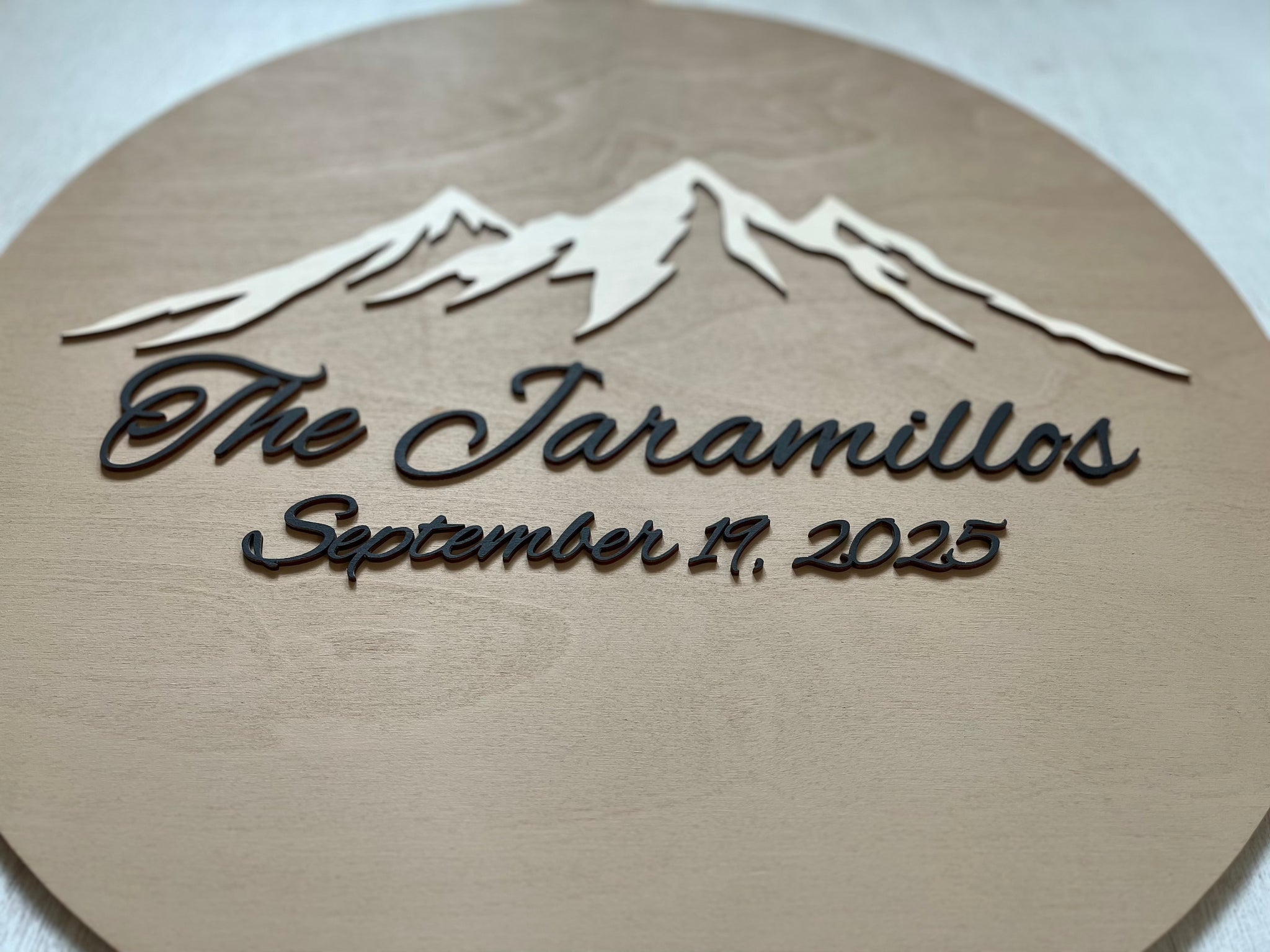 Personalized wooden plaque with mountain design and text on a beige background