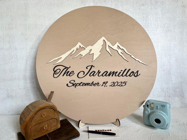 Round decorative plaque with mountain design and text on a stand personalized with a last name and wedding date