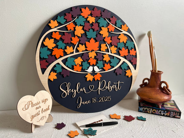 Decorative wedding guest book with colorful maple leaf design and personalized text on a round wooden board.
