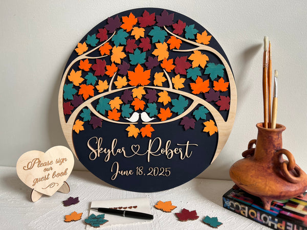Decorative wedding guest book with colorful maple leaf design and personalized text on a round wooden board.
