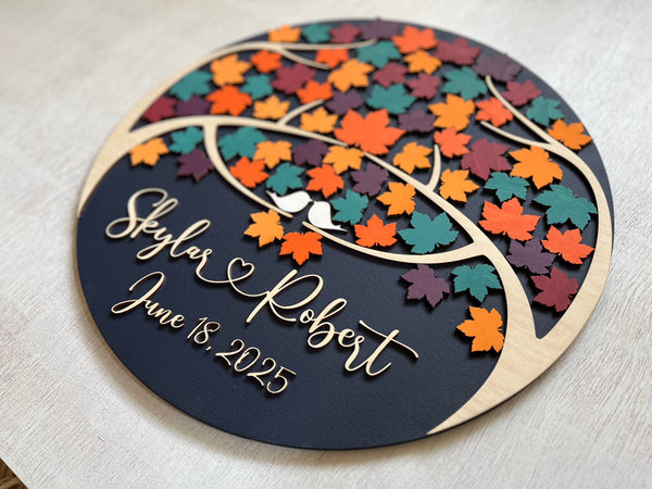 Decorative wedding guest book with colorful maple leaf design and personalized text on a round wooden board.