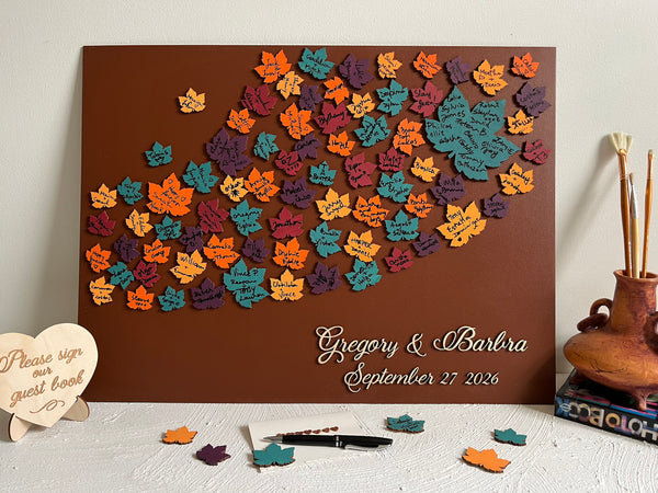Wooden board with colorful maple leaf-shaped cutouts and personalized  names and date- used as a wedding guest book alternative for guest signatures