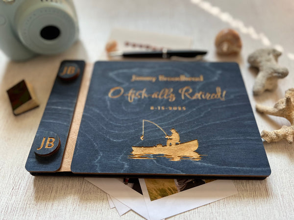Personalized retirement guest book with fishing design and  the engraved text'O fish-ally retired!' text on a wooden surface. Ideal for a retirement celebration with a fishing theme, personalized for the person celebrating the birthday or retirement. The guest book cover is custom engraved with a fishing boat and a fisherman and has custom engraved buttons with the initials of the retiree.