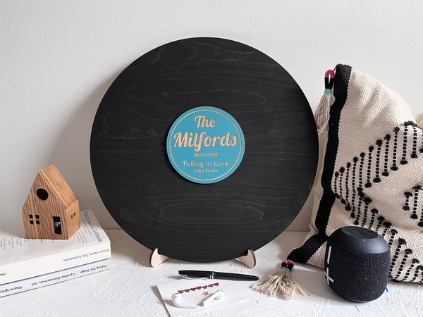 Vinyl music record lookalike sign used as a wedding guest book with personalized names, date and special song title and artist engraved in the middle. The wedding guests sign the record 