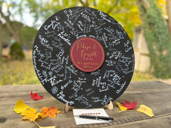 Vinyl music record lookalike sign used as a wedding guest book with personalized names, date and special song title and artist engraved in the middle. The wedding guests sign the record 