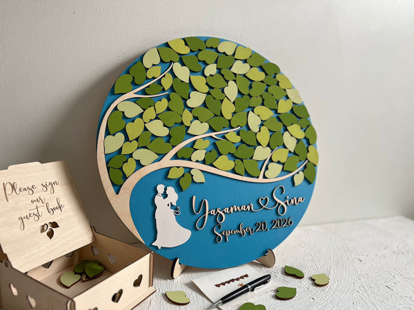 Decorative wedding guest book with tree design and personalized text on a white surface.
