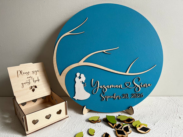 Decorative magnetic wedding sign with tree design and personalized text, accompanied by a wooden guest book box to keep the magnetic leaves