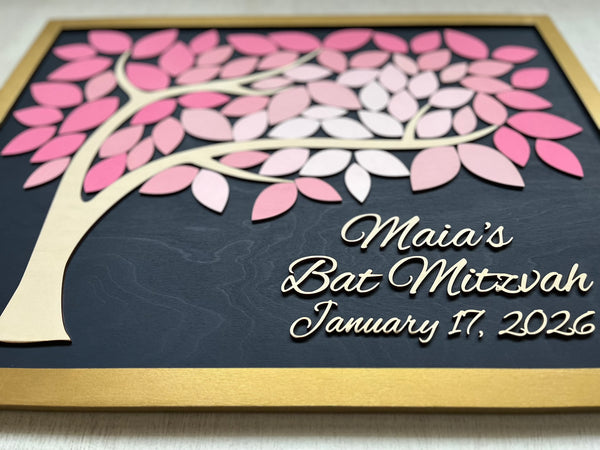 Decorative wall art with a tree and 'Maia's Bat Mitzvah' text on a dark navy blue background with gold frame