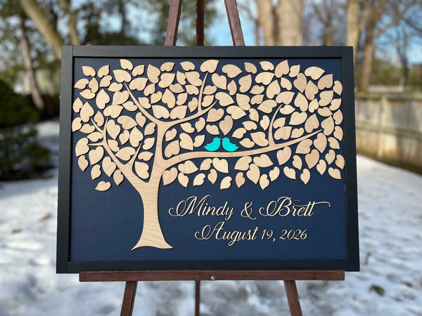 Framed guest book with a tree design, two blue birds, and personalized text on a navy background.