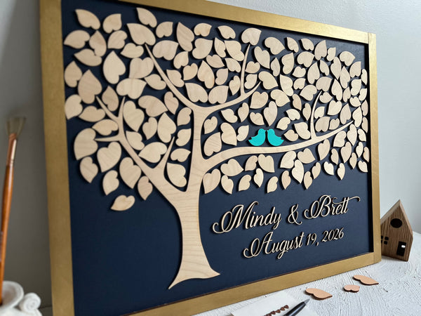 Framed guest book with a tree design, two blue birds, and personalized text on a navy background.