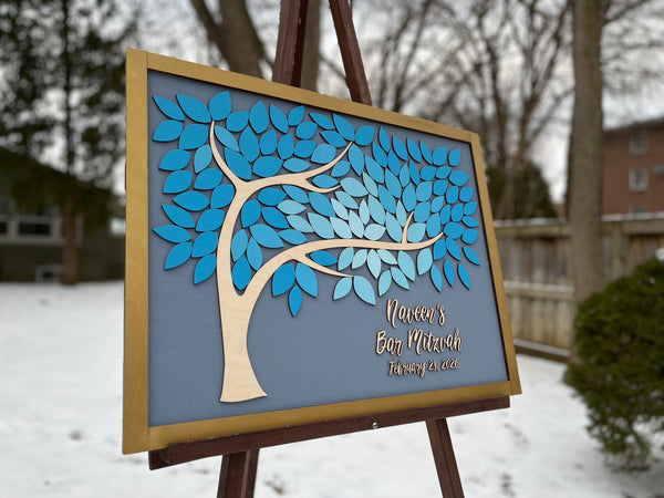 Decorative sign with blue tree design on a stand outdoors in winter
