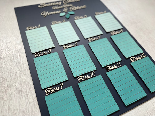 Seating chart for a wedding with tables and names on a dark navy board against a white wall. Made with personalized names for the bride and groom