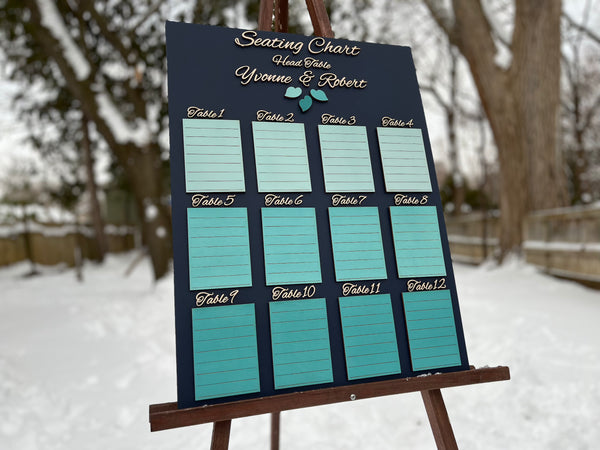 Seating chart for a wedding with tables and names on a dark navy board against a white wall. Made with personalized names for the bride and groom