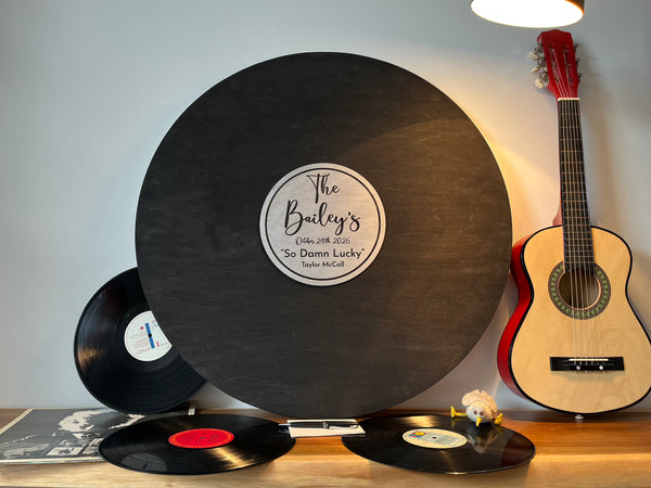 Vinyl records and a guitar on a wooden surface with a gray wall background