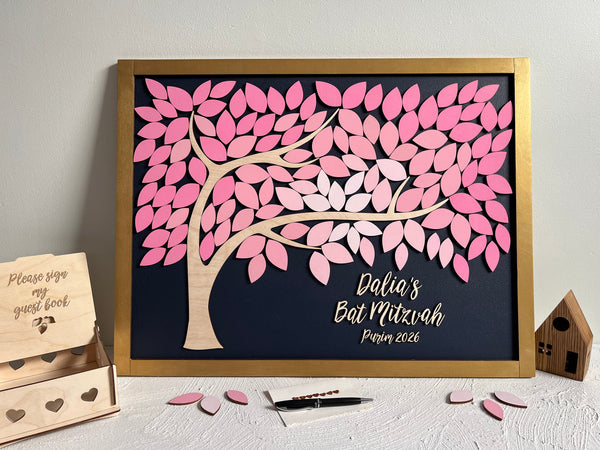 framed guest book alternative made for Bat Mitzvah featuring a tree with leaves to sign. The leaves are magnetic and removable from the magnetic background. The frame is gold but can be customized. The leaves for signing are shades of pink