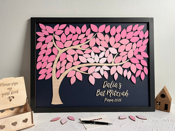 framed guest book alternative made for Bat Mitzvah featuring a tree with leaves to sign. The leaves are magnetic and removable from the magnetic background. The frame is black and the leaves are shades of pink