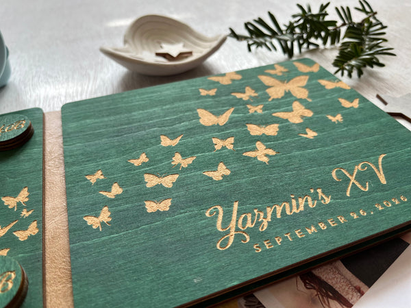 Green notebook with gold butterfly patterns and 'Yazmin's XV' text on a light surface.