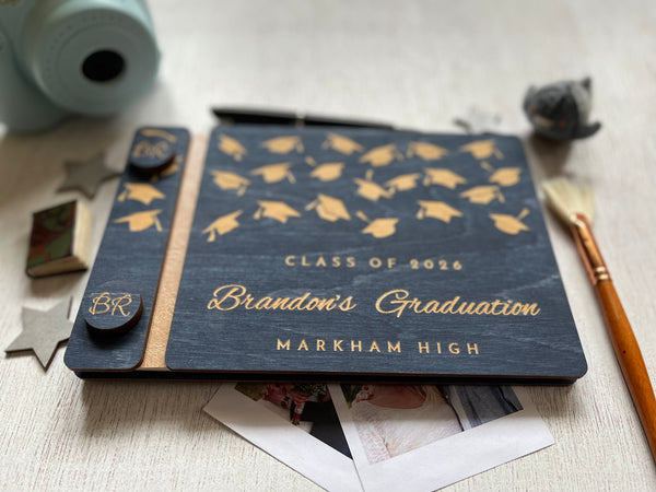 Graduation-themed notebook with engraved text and decorative elements on a light surface.