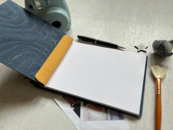 Notebook with pen, camera, and small objects on a textured surface