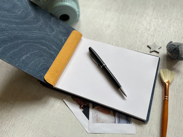 Open notebook with pen and photos on a textured surface