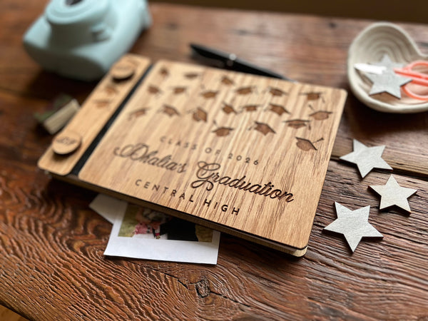 Wooden graduation album with personalized text on a wooden surface with decorative stars.