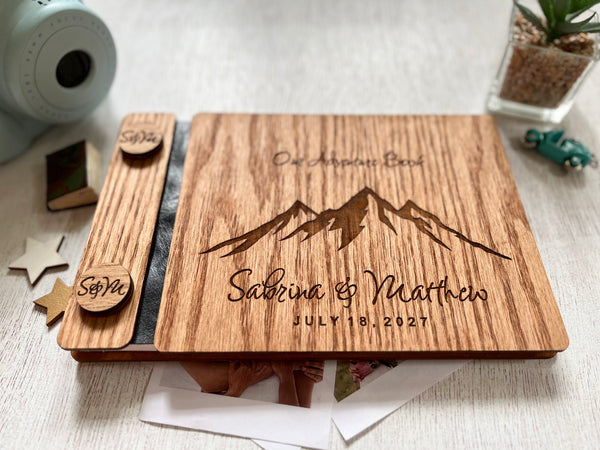 Wooden guest book personalized with mountains and wedding date plus names made of red oak in a brown stain. The text " our adventure book" is engraved on the top side of the guest book
