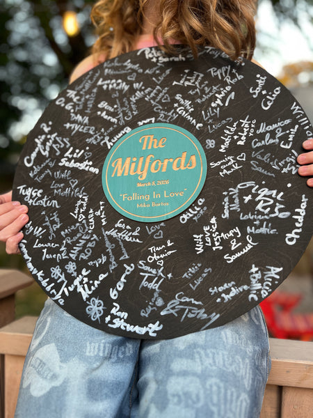 Person holding a personalized vinyl record with signatures on a black background