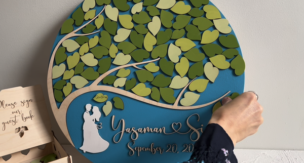 Decorative magnetic wedding sign with tree design and personalized text, accompanied by a wooden guest book box to keep the magnetic leaves