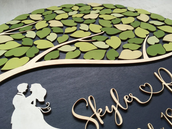 detail with couple silhouette on round guest book with fresh green leaves 