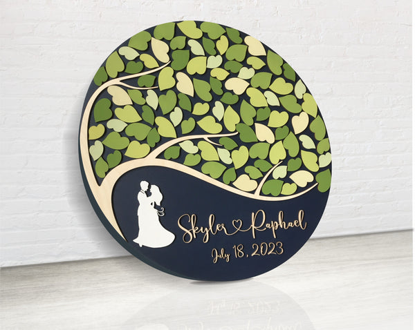 round shaped perosnalized guest book alternative with couple silhouette the names and date of the wedding and a couple silhouette underneath the tree with leaves to sign for guests