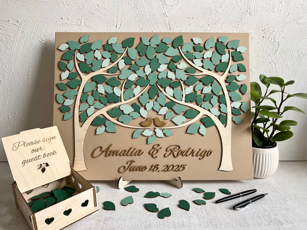 magnetic guest book for wedding made with two trees, personalized names and wedding date in gold font, magnetic leaves for guests to sign and a holder for the board plus a box for the leaves.
