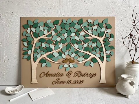 personalized guest book with tan background, two trees, a mix of green leaves, gold birds and golden personalized names and date shown in a creative ensemble 