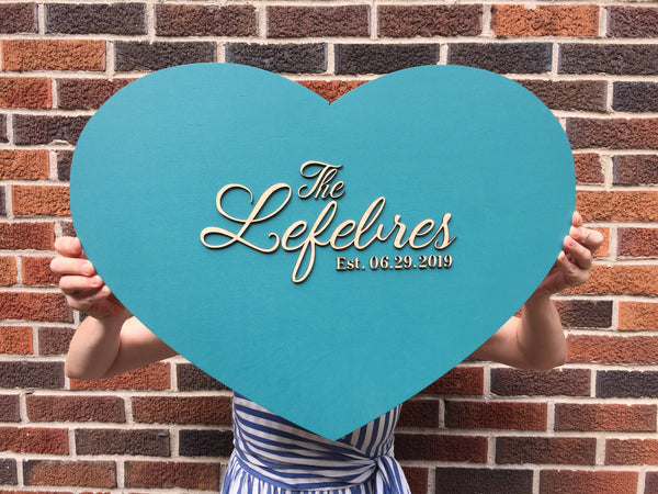 A heart shaped wooden family name sign with personalized details and colors